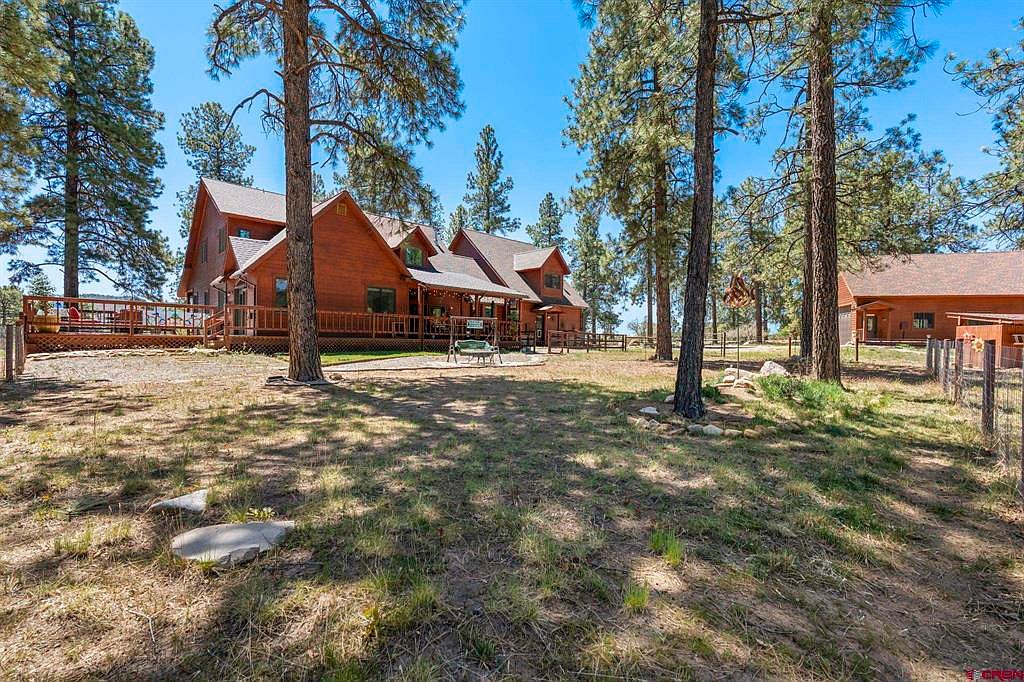 Rear yard view of the home from across three open acres, with the detached garage to the right